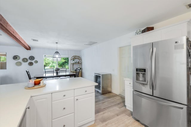 kitchen with visible vents, white cabinets, light countertops, light wood finished floors, and stainless steel fridge