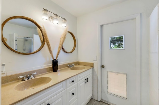 full bathroom with a shower with door, a sink, and double vanity