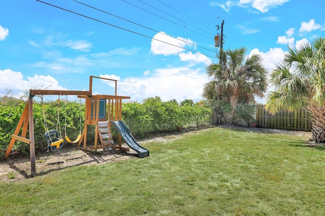 view of playground featuring fence and a lawn