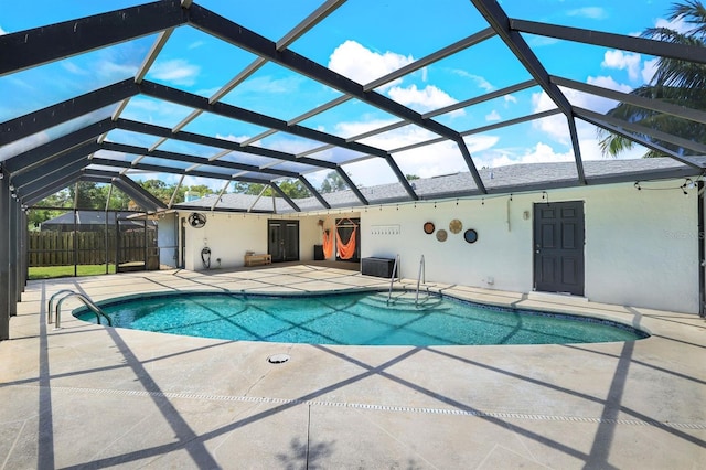 pool with glass enclosure, a patio, and fence