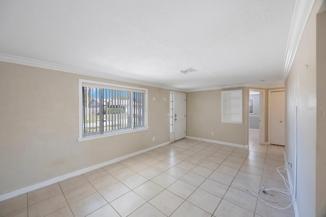 unfurnished room with a textured ceiling, light tile patterned floors, baseboards, and crown molding