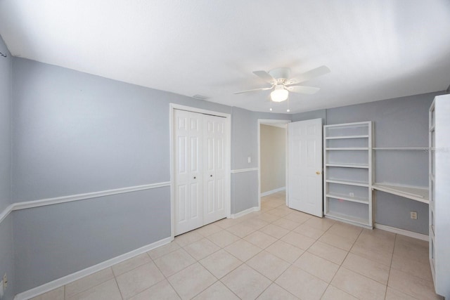 unfurnished bedroom with a closet, light tile patterned flooring, a ceiling fan, and baseboards