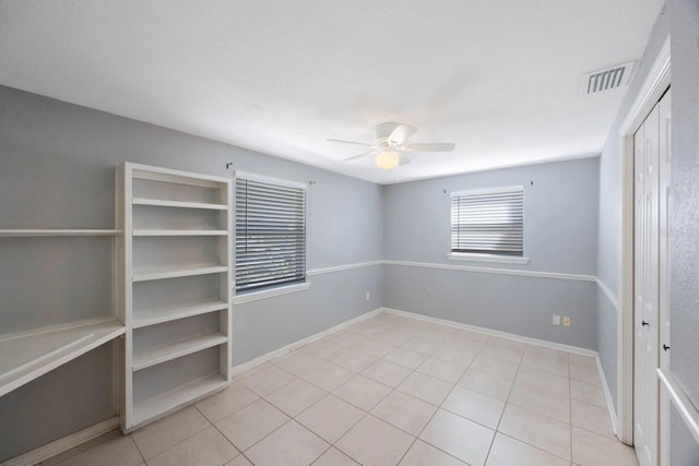 empty room featuring ceiling fan, tile patterned flooring, visible vents, and baseboards