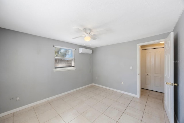 empty room featuring a wall unit AC, ceiling fan, baseboards, and light tile patterned flooring