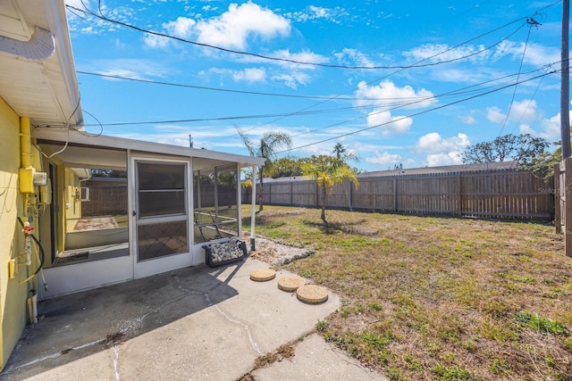 view of yard featuring a sunroom, a fenced backyard, and a patio