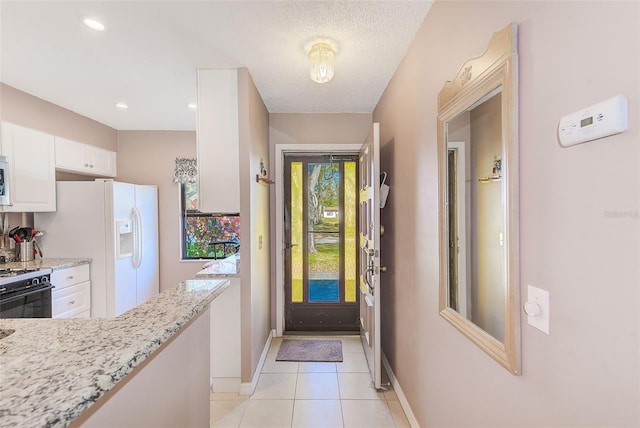 doorway with light tile patterned floors, baseboards, a textured ceiling, and recessed lighting