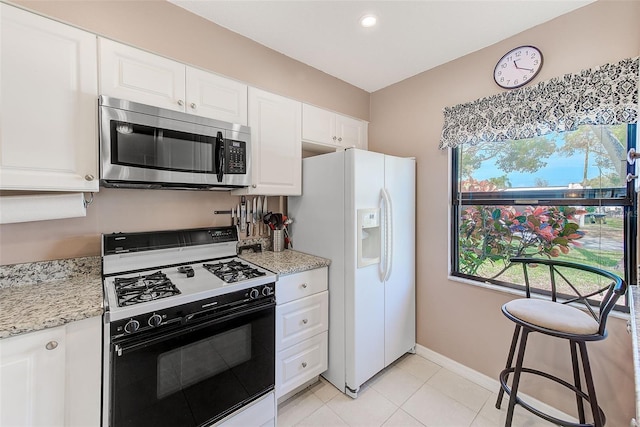 kitchen featuring white cabinetry, baseboards, white fridge with ice dispenser, stainless steel microwave, and gas range