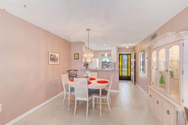 dining space featuring a notable chandelier, a textured ceiling, baseboards, and light tile patterned floors