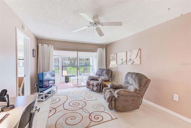 living area with a ceiling fan, tile patterned flooring, a textured ceiling, and baseboards