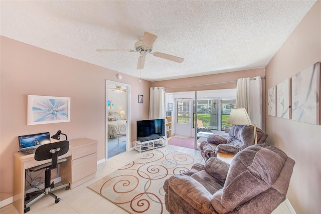 living area with ceiling fan, baseboards, a textured ceiling, and light tile patterned flooring