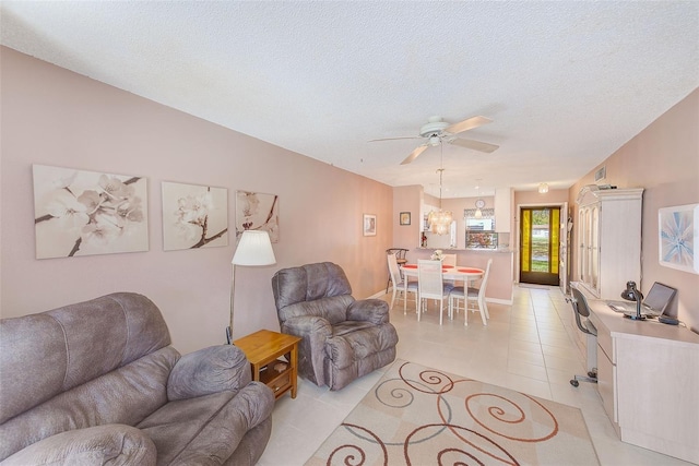 living room with light tile patterned floors, ceiling fan, and a textured ceiling