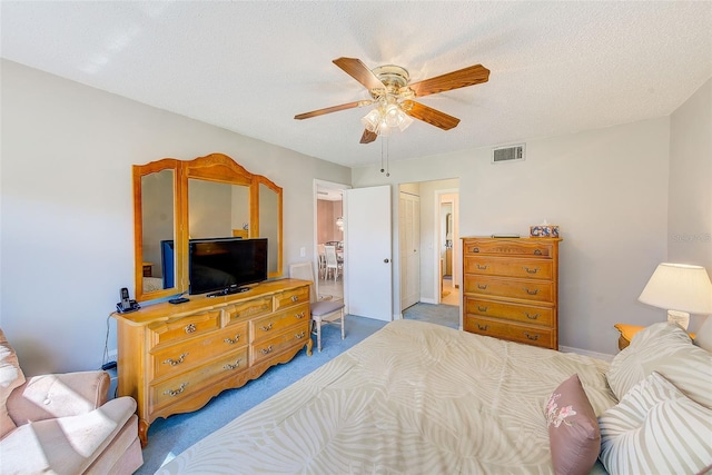 bedroom with a textured ceiling, visible vents, a ceiling fan, carpet, and ensuite bath