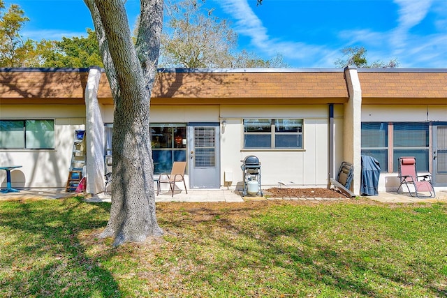 rear view of property with a yard, a patio, and stucco siding