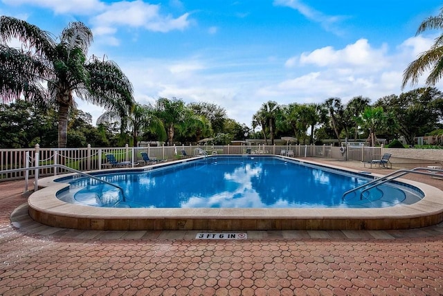 community pool with a patio and fence