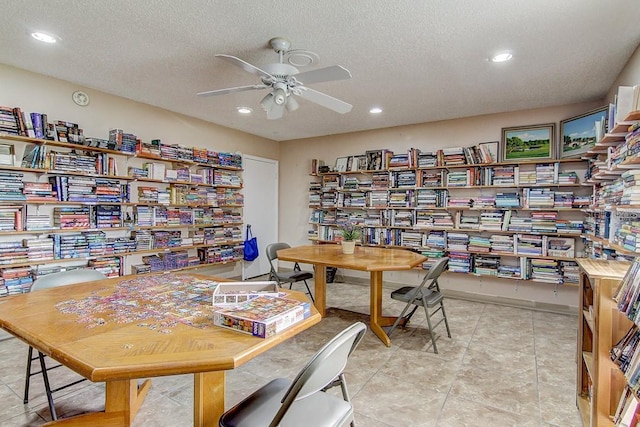 office featuring wall of books, a textured ceiling, and a ceiling fan