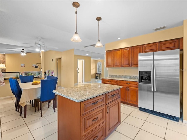 kitchen featuring light stone counters, visible vents, stainless steel fridge with ice dispenser, and light tile patterned floors