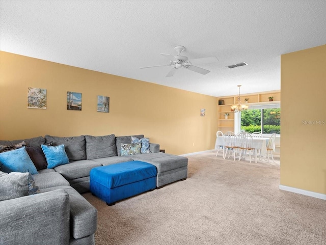 carpeted living area with baseboards, visible vents, a textured ceiling, and ceiling fan with notable chandelier