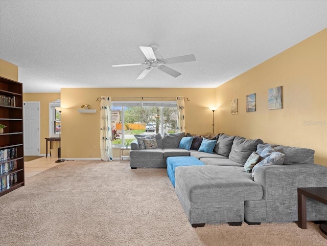 living area featuring a textured ceiling, carpet floors, ceiling fan, and baseboards