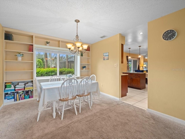 dining area featuring visible vents, light colored carpet, a textured ceiling, a chandelier, and baseboards