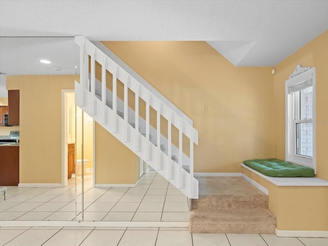 stairs featuring carpet floors, tile patterned flooring, and baseboards