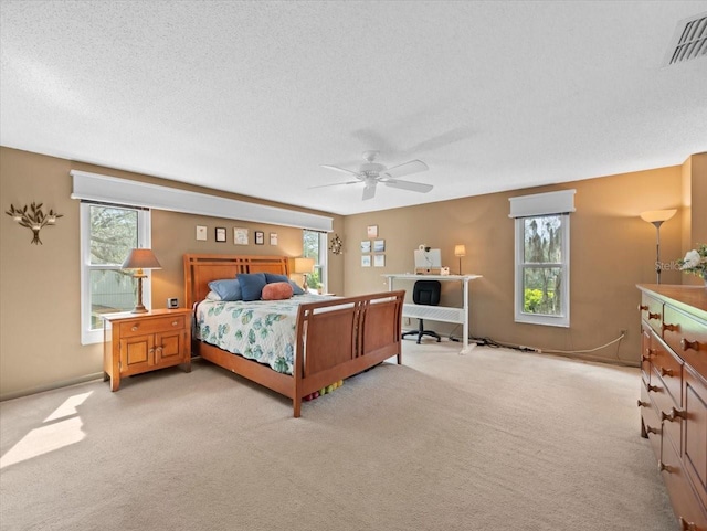 bedroom featuring light colored carpet, visible vents, a textured ceiling, and multiple windows