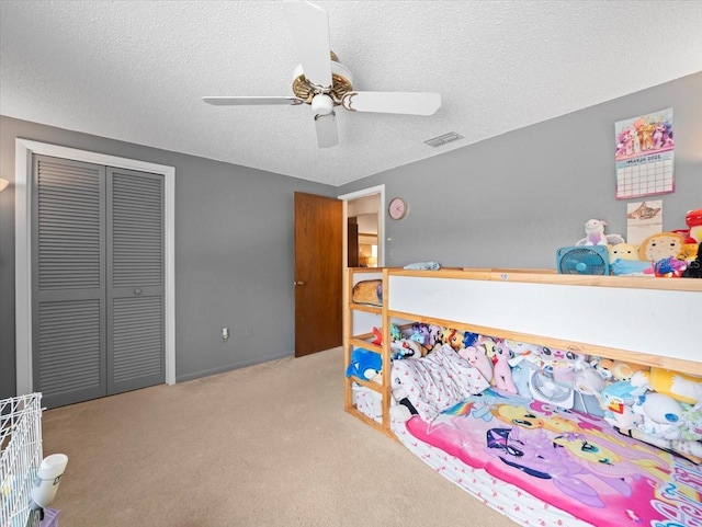 bedroom featuring carpet floors, a closet, ceiling fan, and a textured ceiling