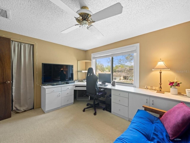 office space with light carpet, a textured ceiling, visible vents, and a ceiling fan