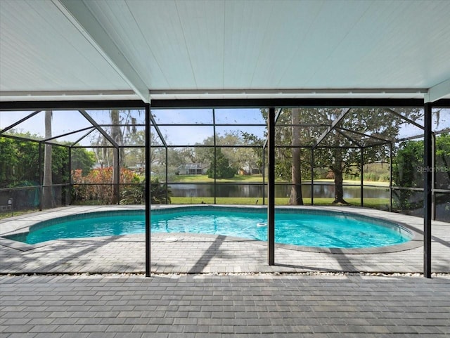 outdoor pool featuring glass enclosure, a patio area, and a water view