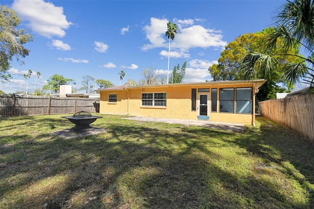 back of property with an outdoor fire pit, a lawn, a fenced backyard, and stucco siding