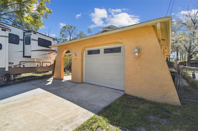 garage with concrete driveway and fence