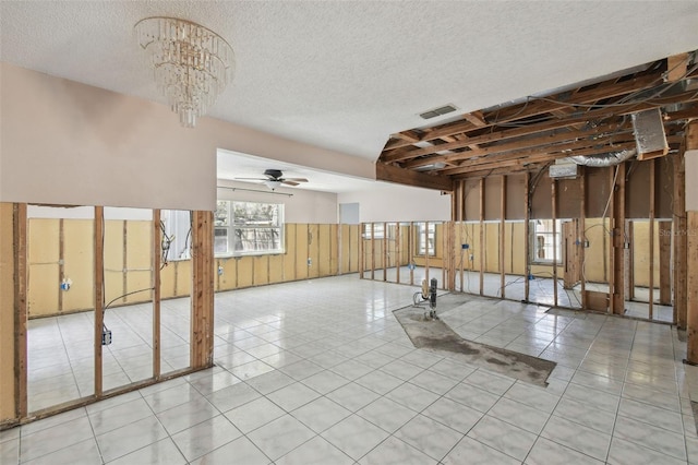 interior space featuring tile patterned flooring, visible vents, a textured ceiling, and ceiling fan with notable chandelier