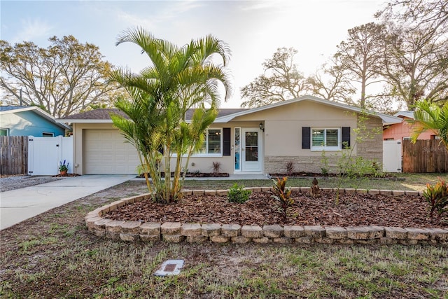 ranch-style house featuring a garage, concrete driveway, a gate, fence, and stucco siding