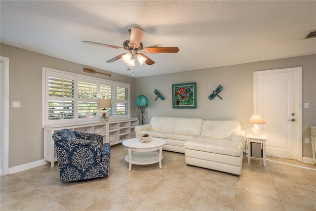 living room featuring ceiling fan, light tile patterned floors, a textured ceiling, and baseboards