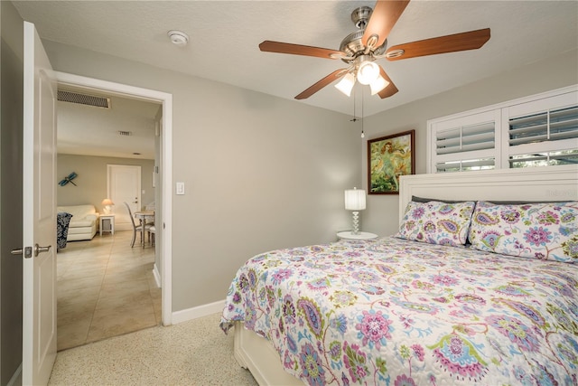 bedroom featuring baseboards, dark aggregate flooring, and a ceiling fan