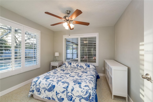 bedroom with multiple windows, baseboards, a ceiling fan, and dark speckled floor
