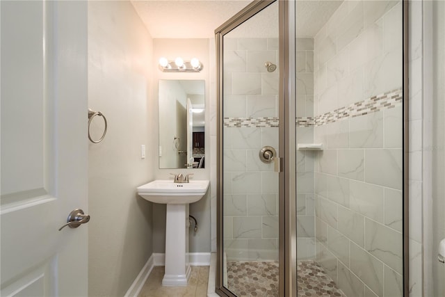 full bathroom featuring a stall shower, a sink, and baseboards