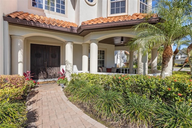 property entrance featuring covered porch, stucco siding, and a tile roof