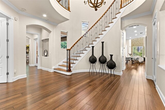 entryway featuring baseboards, arched walkways, wood finished floors, and ornamental molding