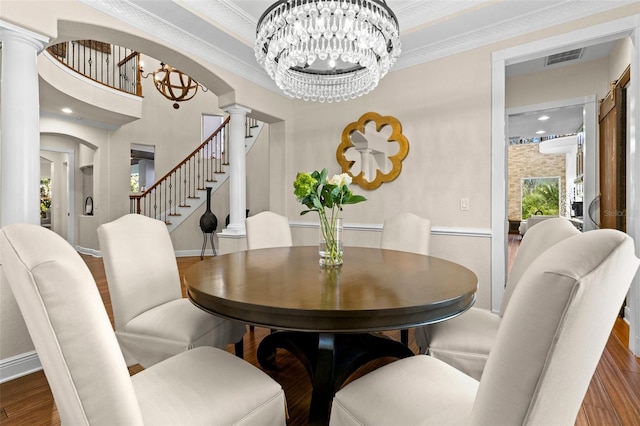 dining area with visible vents, stairs, decorative columns, an inviting chandelier, and wood finished floors