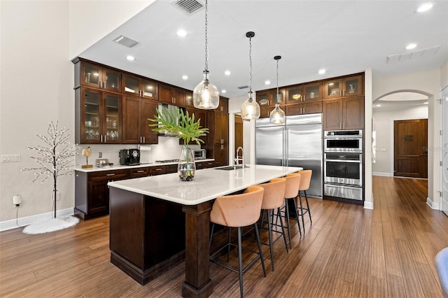 kitchen with visible vents, arched walkways, a sink, stainless steel appliances, and a warming drawer