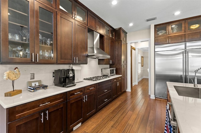 kitchen featuring visible vents, stainless steel appliances, light countertops, and wall chimney range hood