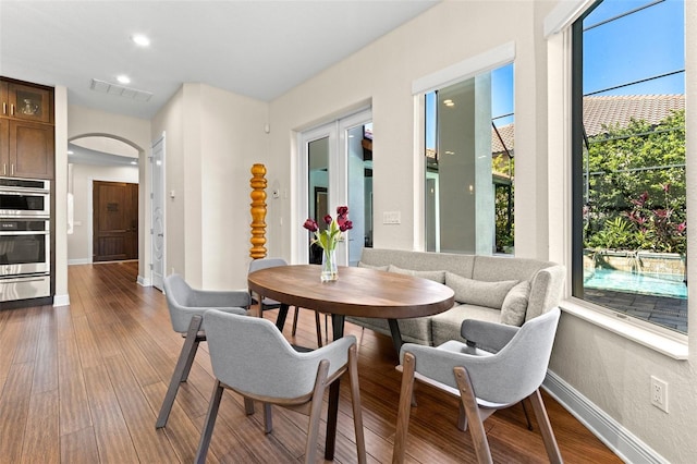 dining area featuring visible vents, wood finished floors, recessed lighting, arched walkways, and baseboards