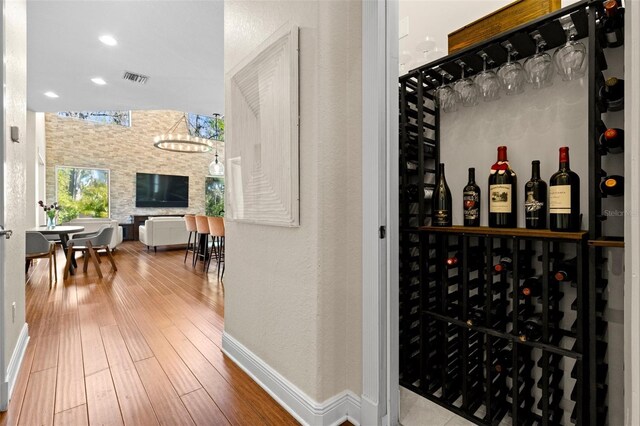 wine room featuring baseboards, visible vents, recessed lighting, a bar, and hardwood / wood-style flooring