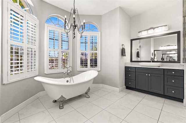 full bath with tile patterned flooring, baseboards, a chandelier, a freestanding bath, and vanity