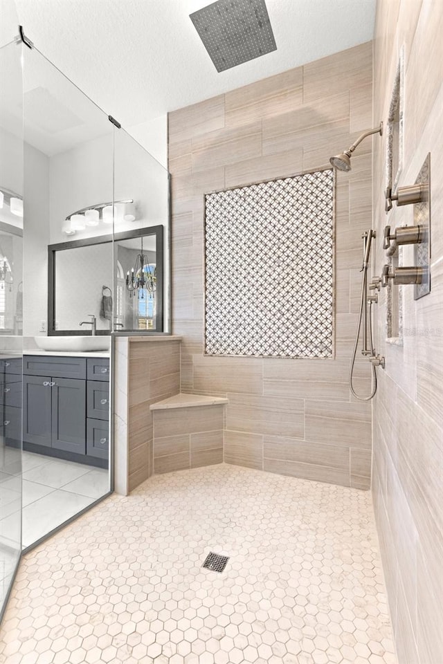 bathroom featuring tile patterned floors, tiled shower, a textured ceiling, and vanity