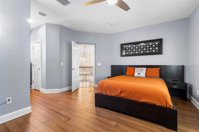 bedroom featuring ceiling fan, visible vents, baseboards, and wood finished floors