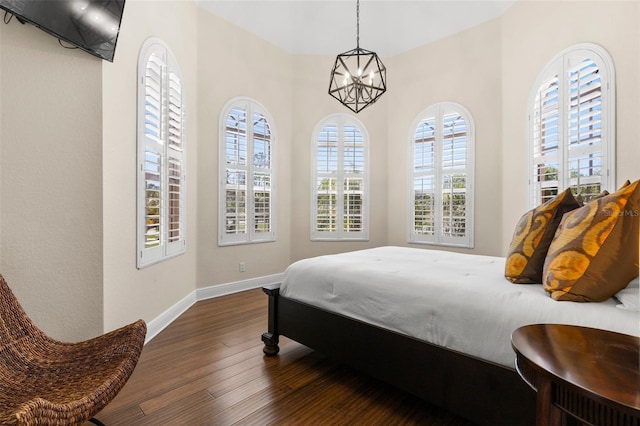 bedroom with baseboards, a notable chandelier, and dark wood-style flooring