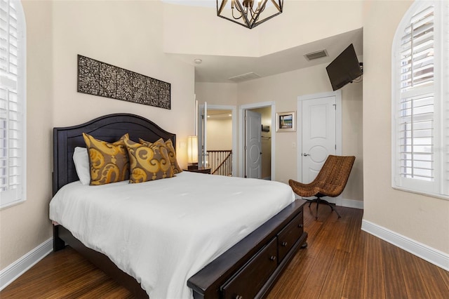 bedroom with visible vents, baseboards, dark wood finished floors, and a chandelier