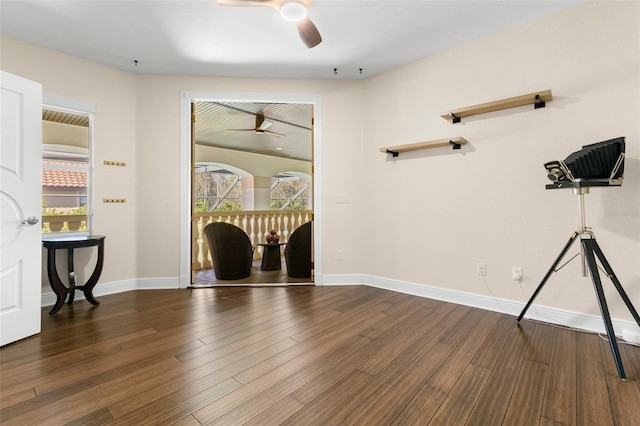 spare room featuring baseboards, dark wood-style floors, and a ceiling fan