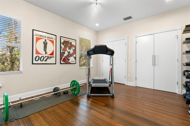 exercise area with dark wood finished floors, baseboards, and visible vents